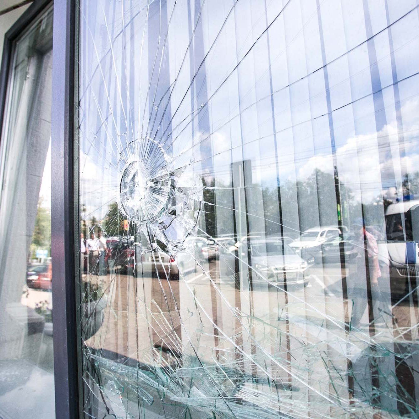 Broken glass window of the modern building reflecting blue sky